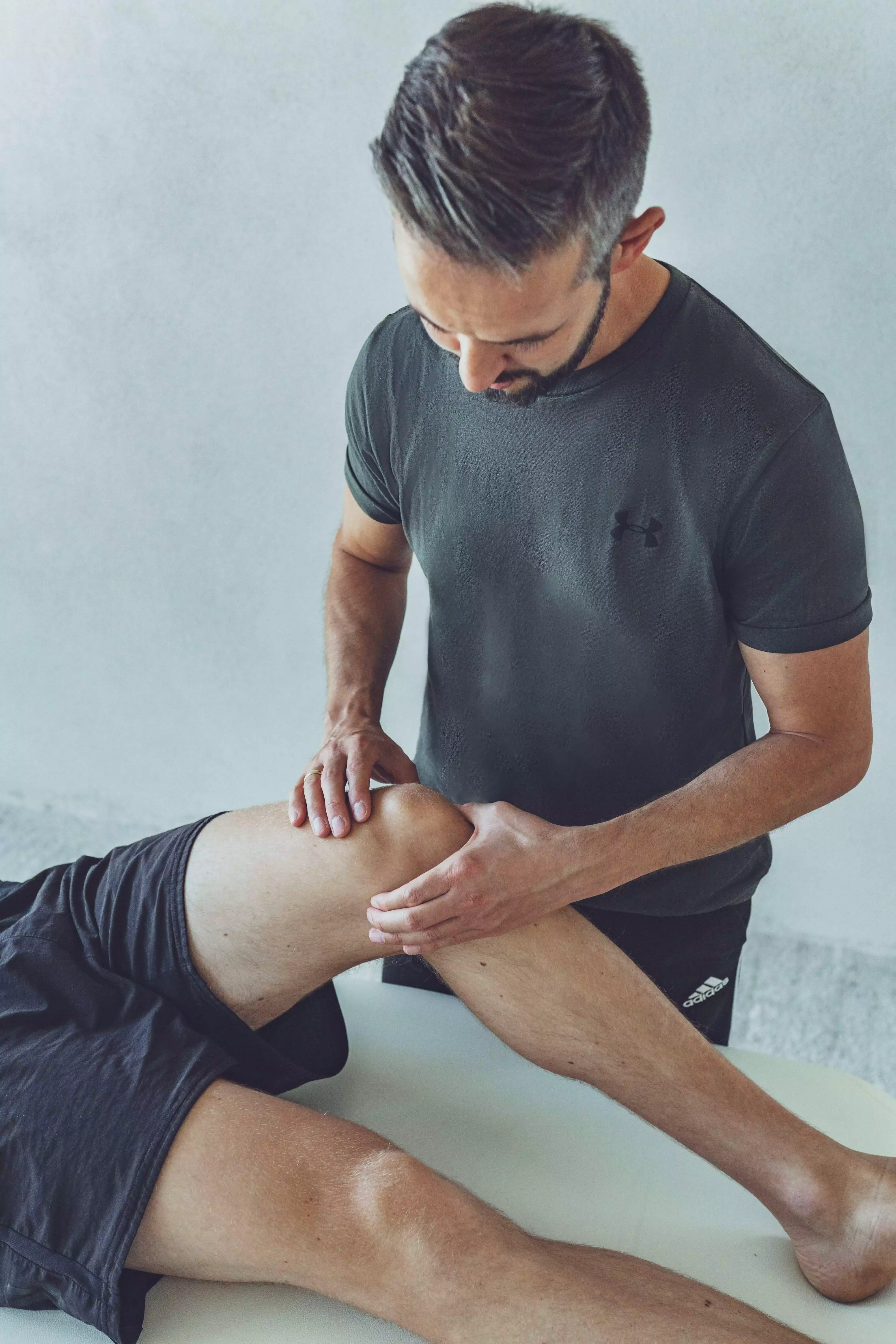 Therapeut mit Patient mit Beschwerden am Knie