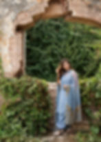 Woman in blue embroidered salwar kameez poses near ancient stone archway