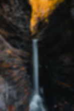 Waterfall cascading through autumnal gorge