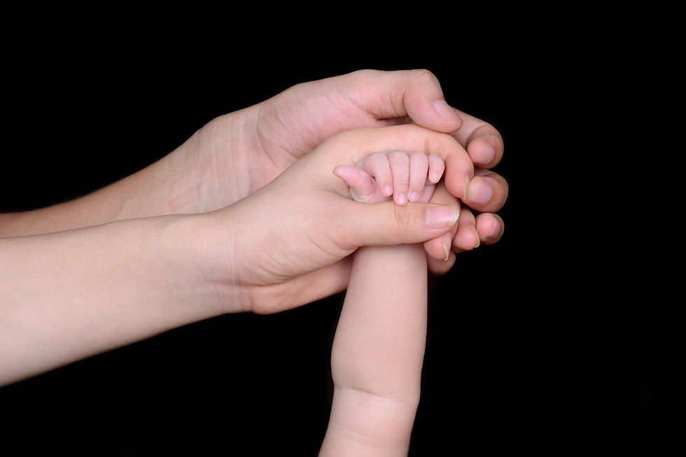 Parents' hands gently holding their newborn baby's tiny hand