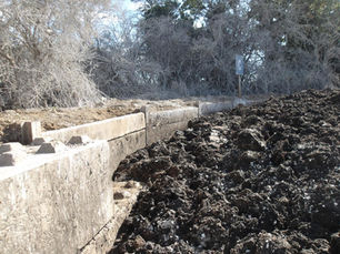 Photo of piles of sewage sludge being stored outdoors surrounded by a temporary concrete wall