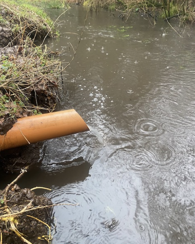 water flowing from a pipe in the bank into a stream