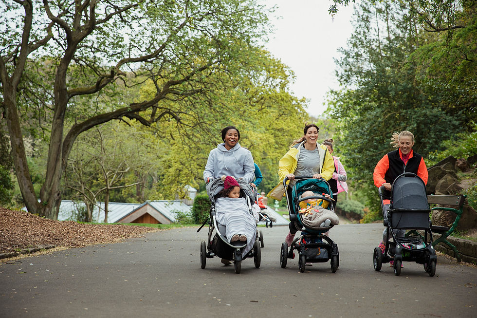 A group of mothers with strollers walking down a forested road