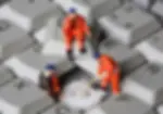 three tiny toy figures of workmen repairing a giant keyboard key