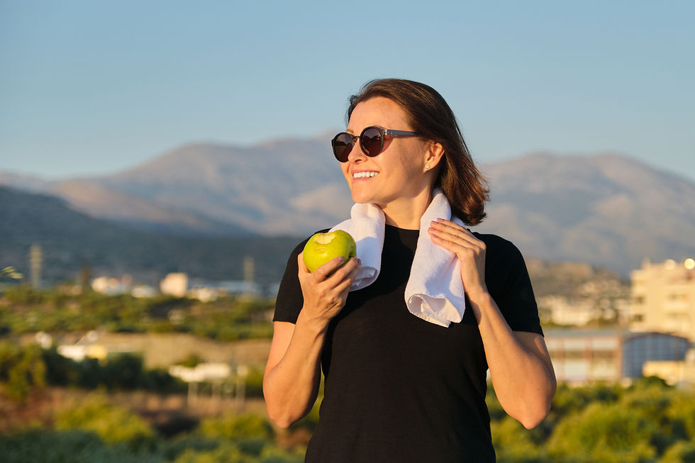 A woman holding a towel and a green apple is smiling in the sunshine, highlighting the importance of staying hydrated for maintaining healthy, glowing skin in the summer heat.