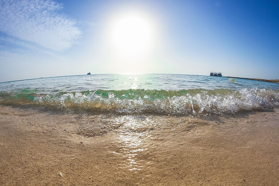 A sunny beach with gentle waves rolling onto the sandy shore, evoking a sense of relaxation and the perfect summer setting, representing the tranquility and rejuvenation that can be achieved through Revital Med Spa's advanced skincare treatments.