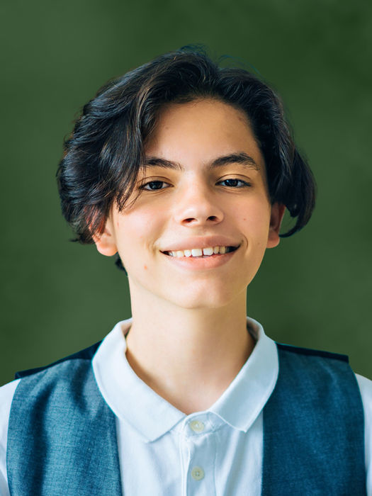 School portrait of a young boy in a teal top on a classic Evergreen background by Instant School Photos