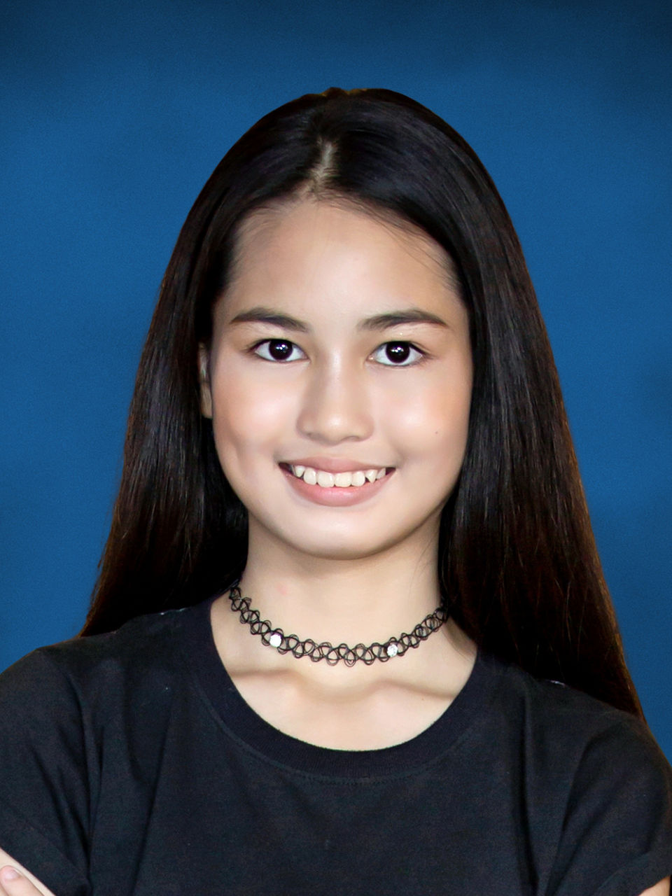 Student portrait of a teenage girl with long dark hair on a Horizon blue studio background