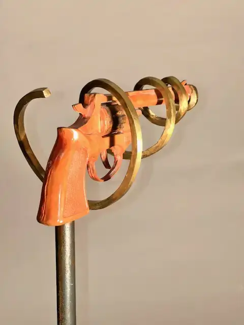 sculpture de bronze d'un fusil couleur rouge avec une spirale de biais , série violence désarmée par l'artiste De Leclerc