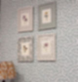 Four floral prints in patterned frames hang on a textured wall. A colorful lamp base is in view, creating a vintage aesthetic. Wrapped Framing Workshop with Polly Ruffman aka Polly Wolly Doodles