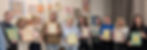 Group of smiling women holding framed art in a gallery with colorful paintings on the wall. The mood is cheerful and lively. Wrapped Framing Workshop with Polly Ruffman aka Polly Wolly Doodles