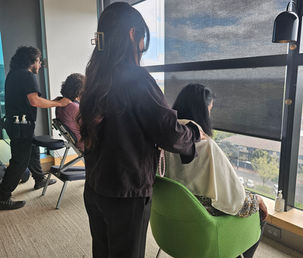 A Cozy & Coco therapist providing a seated shoulder massage to an office employee beside large windows.