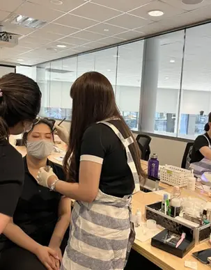 Guests and beauty professionals taking part in a pampering session in a bright office.