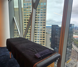 A portable office massage table set up beside floor-to-ceiling windows with city views.