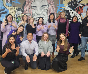 Event participants posing for a group photo in front of a colourful mural.