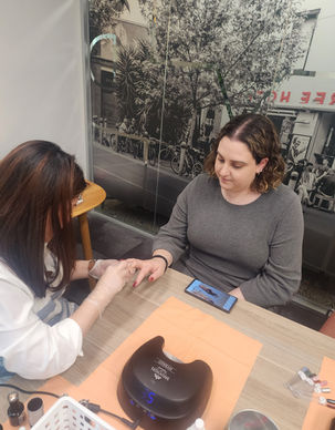 A nail technician giving a seated office guest a manicure across a treatment table.