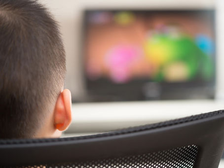 Man viewed from behind watching a flickering television screen in a dark room, representing parasocial attachment and media influence