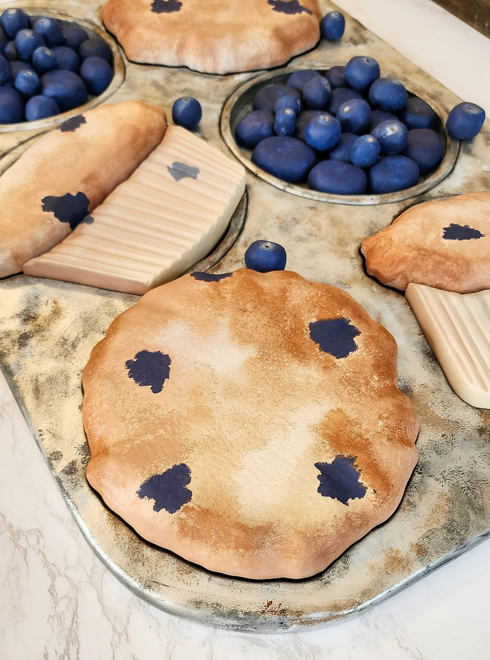 Thumbnail: Overhead view of the hand painted and carved blueberry muffins made out wood.