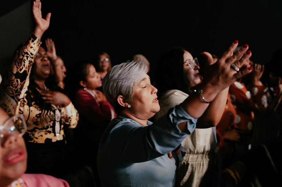 Congregation of women with hands raised, eyes closed in heartfelt worship.