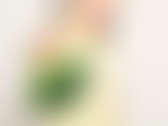 A girl holding a bunch of broccoli away from herself in disgust