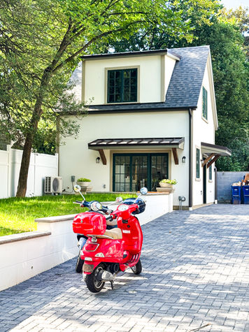 Two‑story cream‑colored ADU with dark trim and brick driveway