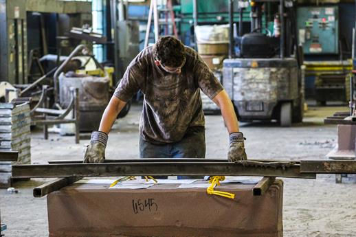 A foundry worker grinds or finishes a cast metal piece, smoothing out imperfections.