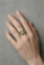 Hand wearing silver wax carved ring with green zircon on concrete