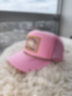 Detailed view of pink trucker hat with Lucky or Not embroidered patch and gold trim