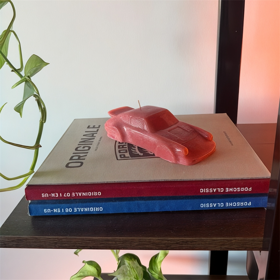Poppy Rouge handmade sculptural car candle styled on automotive books with soft warm lighting and greenery
