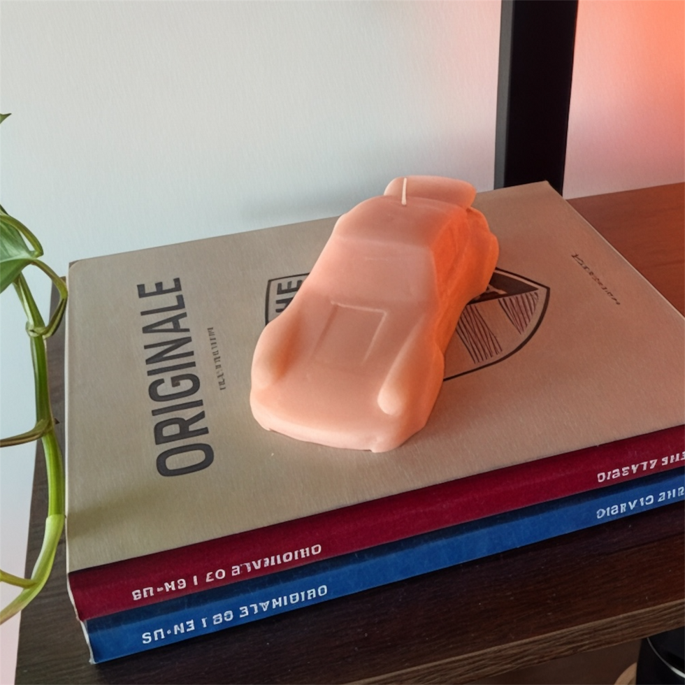 Petal Pink handmade sculptural car candle styled on automotive books with soft warm lighting