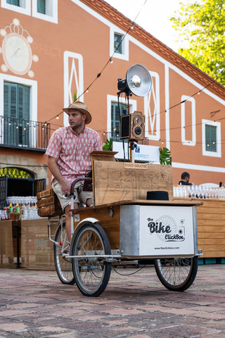 Food truck vintage sirviendo bebidas en un evento: Camioneta adaptada como bar con un camarero atendiendo.
