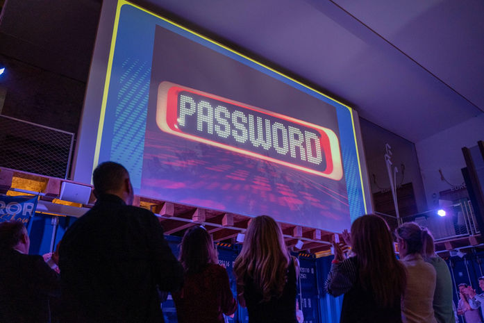 Proyección de "PASSWORD" en una pantalla durante una actividad de equipo – Dinámica interactiva basada en un famoso juego de palabras.