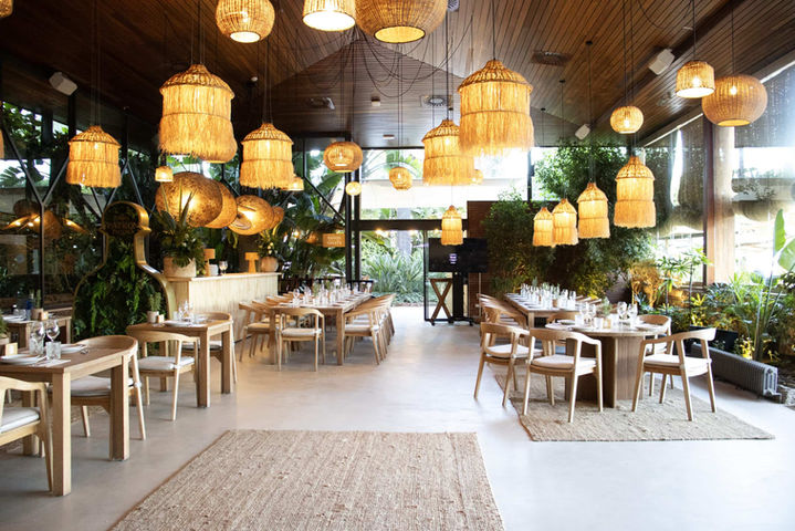 Salón interior con iluminación cálida y detalles en madera: Restaurante con decoración bohemia y acogedora.
