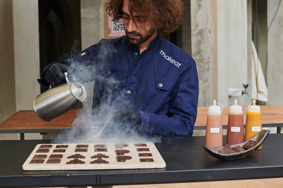 Chef elaborando postres con nitrógeno líquido en una mesa de degustación – Experiencia gastronómica molecular en evento exclusivo.