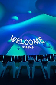 Experiencia inmersiva en un domo con proyección 360°, con sillas blancas alineadas y un mensaje de bienvenida en la pantalla.