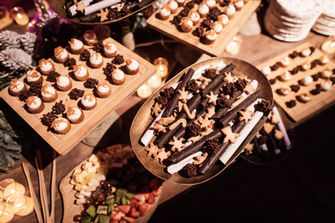 Dessert table with mini cakes, chocolates and sweet treats creatively arranged on raised trays.