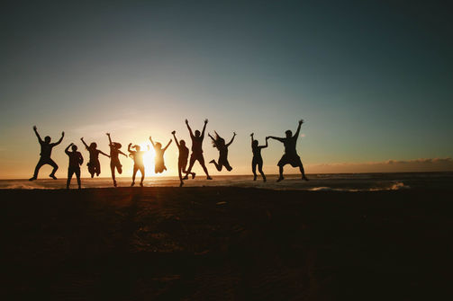 Actividad de motivación al atardecer con un grupo saltando en la playa, representando energía y positivismo.