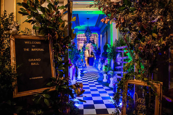 Fairy-tale-themed illuminated entrance to a corporate event, with a hallway decorated in the style of Alice in Wonderland.
