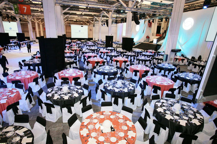 Banquete corporativo en Fira Barcelona con mesas decoradas y disposición elegante para cenas de gala, convenciones y eventos de empresa. Cenas de gala en Barcelona, eventos corporativos en Fira, espacios para convenciones y networking.