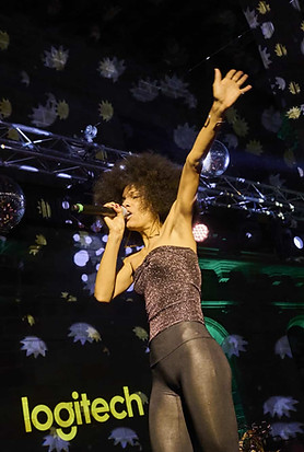 Presentación musical en vivo en Integrated Systems Europe (ISE) Barcelona patrocinado por Logitech – Cantante sobre el escenario con luces dinámicas y fondo de marca, creando una atmósfera inmersiva.