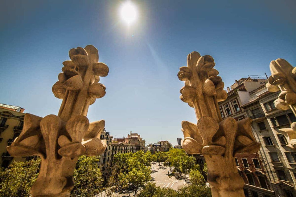 Detalle arquitectónico modernista con vistas de Barcelona: Escultura decorativa en primer plano con la ciudad al fondo.