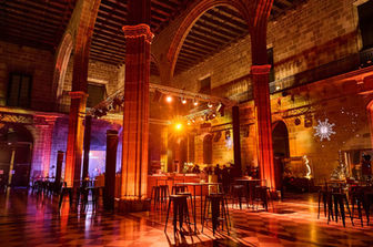 Salón decorado con iluminación cálida, lámparas de estilo industrial y muebles elegantes, generando una atmósfera acogedora.