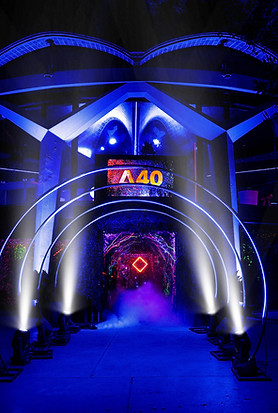 Futuristic entrance decorated with neon-lit arches and the "A40" logo in the background, surrounded by smoke effects and vibrant color projections, ideal for a nighttime event.