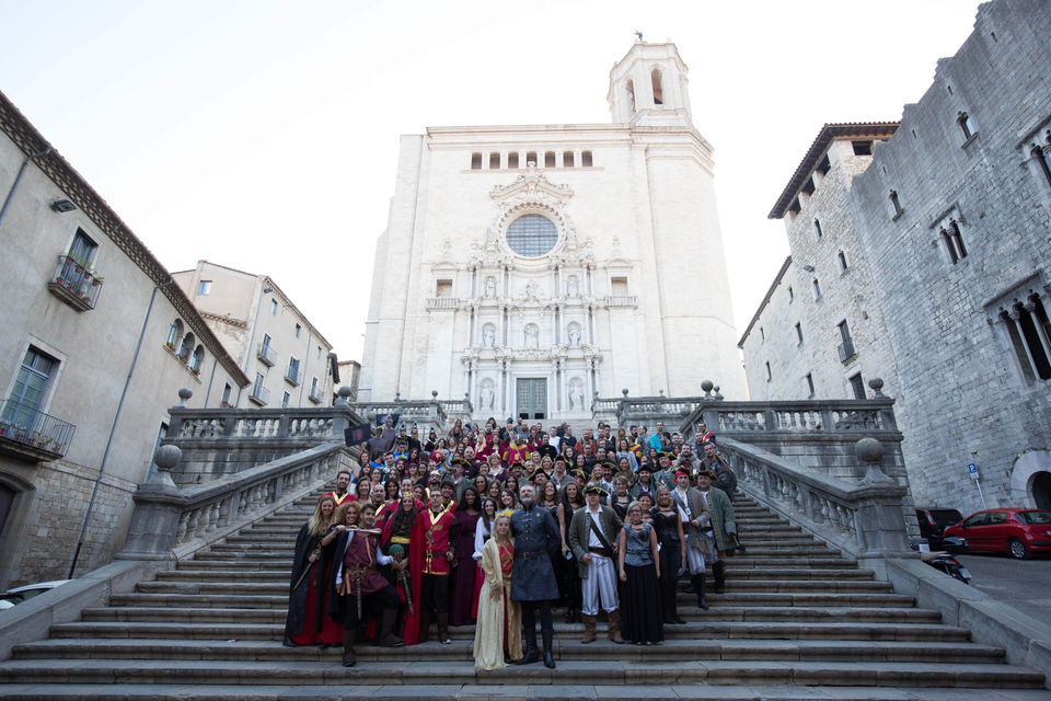 Grupo de personas con trajes medievales en las escaleras de una catedral – Recreación histórica en un evento temático medieval.