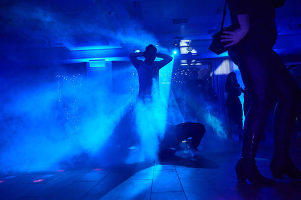 Espectáculo artístico con iluminación azul y humo, con performers realizando una rutina enérgica.