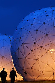 Estructuras geodésicas iluminadas en un evento nocturno al aire libre, con siluetas de personas caminando frente a los domos futuristas.