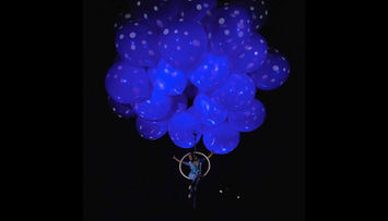 Instalación artística con globos translúcidos iluminados en tonos azules, formando una estructura flotante.