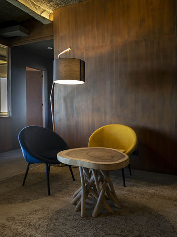 Rincón acogedor con sillones modernos: Pequeño espacio con sillas de diseño en amarillo y negro, junto a una mesa redonda y lámpara de pie.