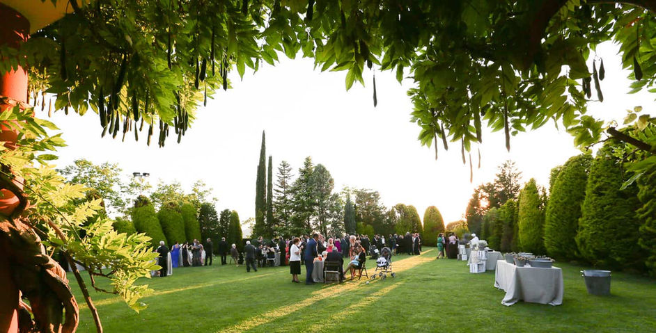 Recepción en el jardín con invitados en fila: Evento formal en un entorno rodeado de árboles.
