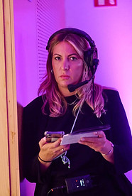 Woman with headphones and tablet coordinating an event with purple lighting – Producer or event technician in full management of a live production.